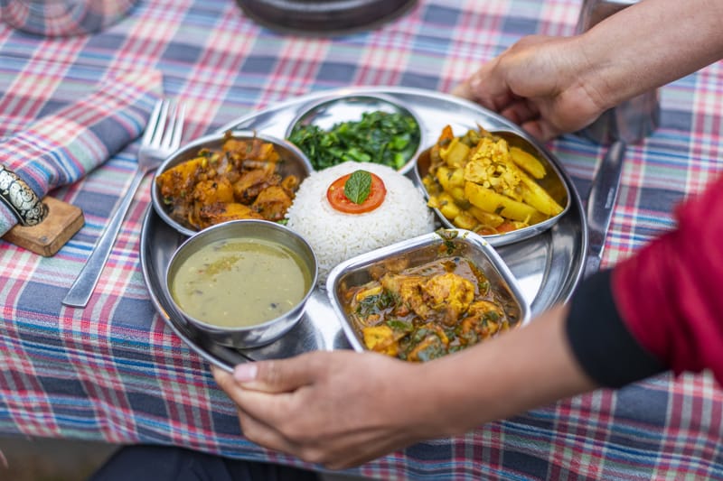 Dal Bhat, a traditional Nepalese meal made of various dishes including rice, lentil soup, spinach, curried vegetables and meat.