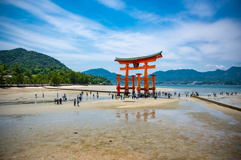 Visitors walk around the base of the torii gate at Itsukushima Shrine at low tide