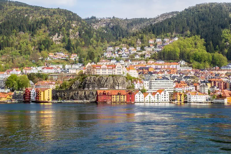 The colourful timber facades of Bryggen line Bergen's historic waterfront, with the city's mountain backdrop rising behind.
