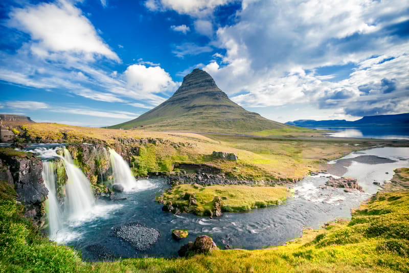 Kirkjufell Mountain rising above green hills with a river flowing nearby on the Sn&aelig;fellsnes Peninsula, Iceland