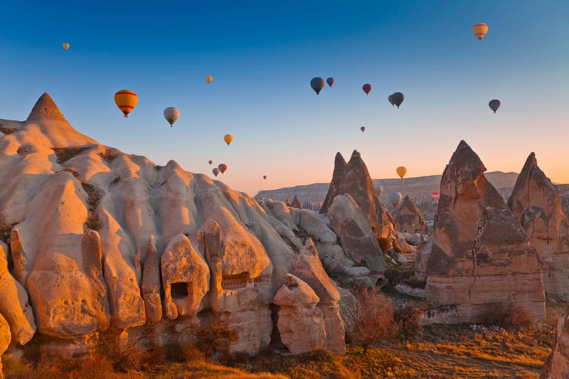 Hot-air balloons over Cappadocia's fairy chimneys at sunrise, one of the most sought-after May travel experiences in Turkey.