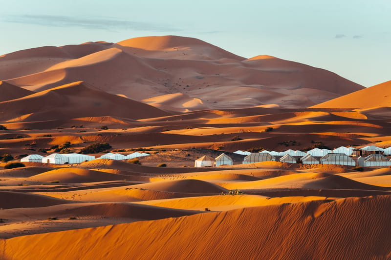 First light breaks over the tents as the dunes turn gold.