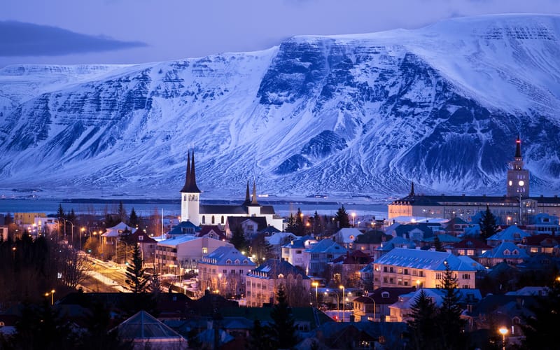 City skyline of Reykjavik, Iceland at dusk, with colourful buildings and distant mountains under an evening sky
