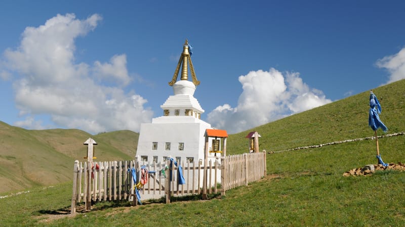 A Buddhist stupa with prayer flags on a steppe, one of the rural sites that shape a Mongolia travel cost
