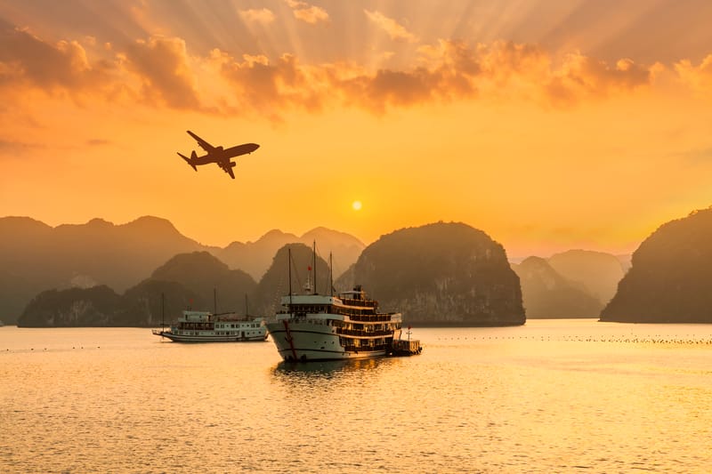 Luxury holiday cruise ships sailing through Ha Long Bay, Vietnam at sunset, surrounded by limestone islands