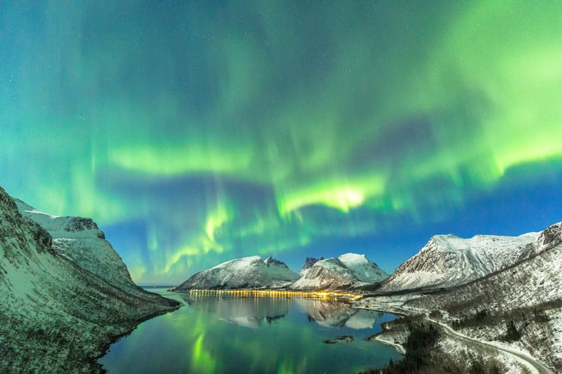 The aurora borealis ripples across the night sky above a Norwegian fjord in northern Norway.