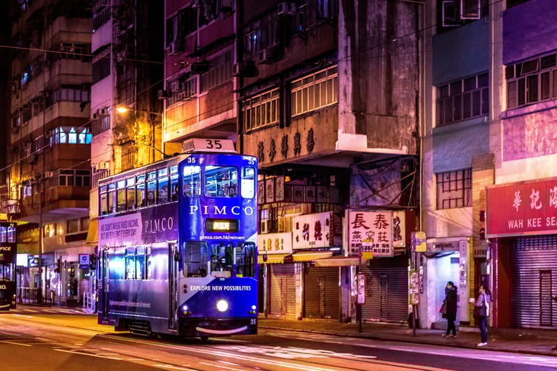 Hong Kong lights up at night with the iconic double-decker tram moving along the streets