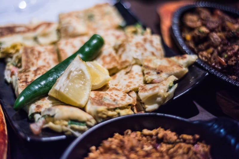 Mutabbaq is pan-fried until golden and crisp, then served hot with a tangy dipping sauce.