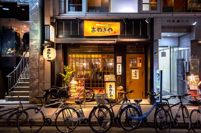 Evening street scene in Hiroshima with bicycles parked near restaurants and shops